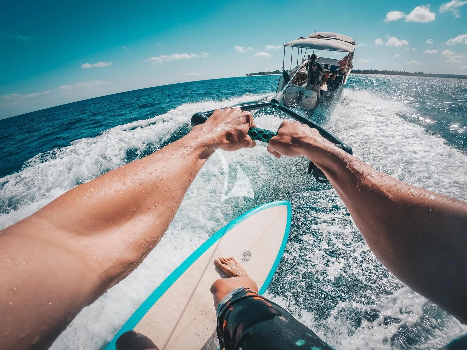 a person holding a surfboard and a boat in the background aboard KUDANIL EXPLORER Yacht for Sale