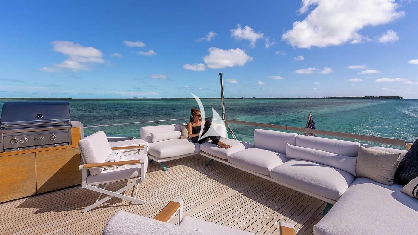 a person sitting on a couch on a deck overlooking the ocean aboard GATSBY Yacht for Charter