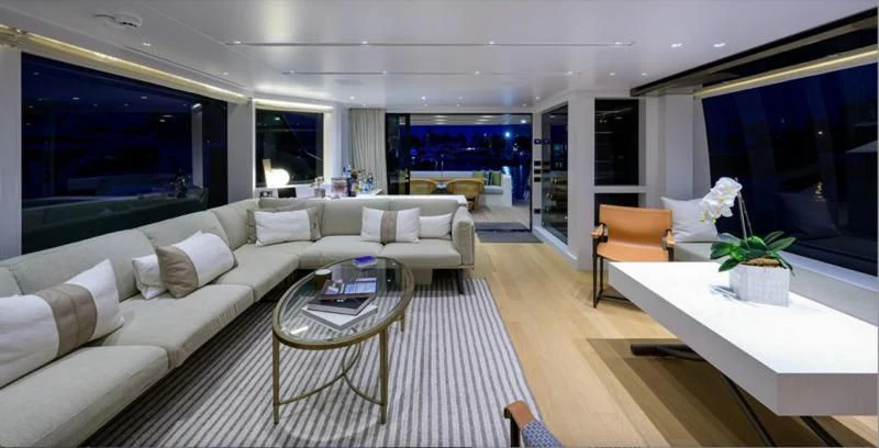 a living room with a large white sofa and a large window aboard GATSBY Yacht for Charter