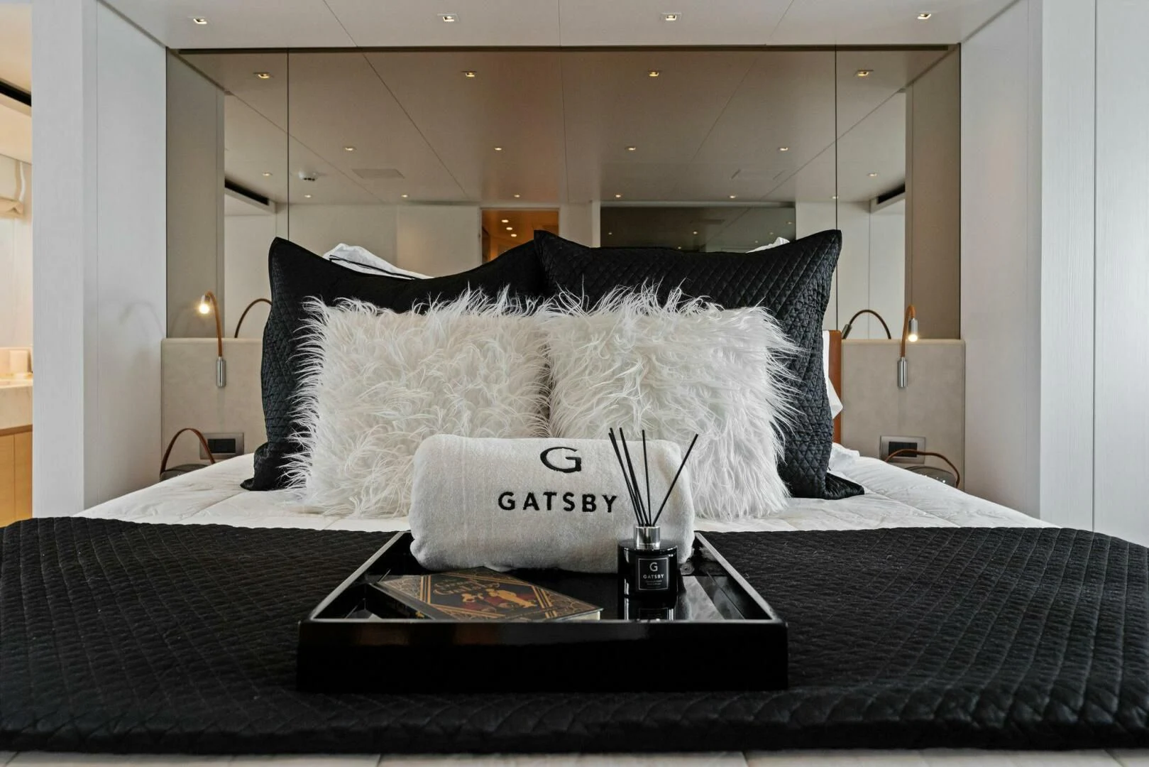 a bed with a black and white pillow and a white pillow on it aboard GATSBY Yacht for Charter