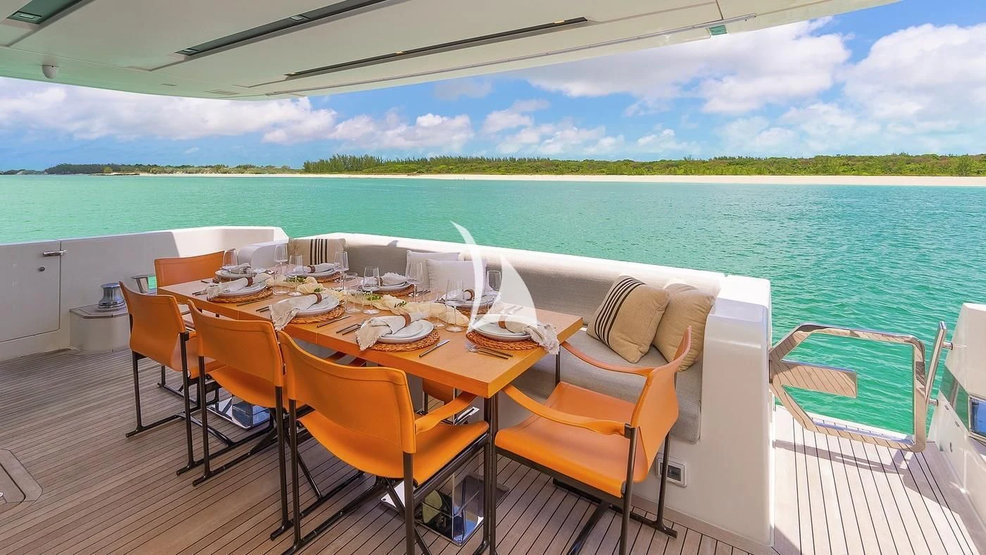 a table set for a meal on a deck overlooking a beach aboard GATSBY Yacht for Charter