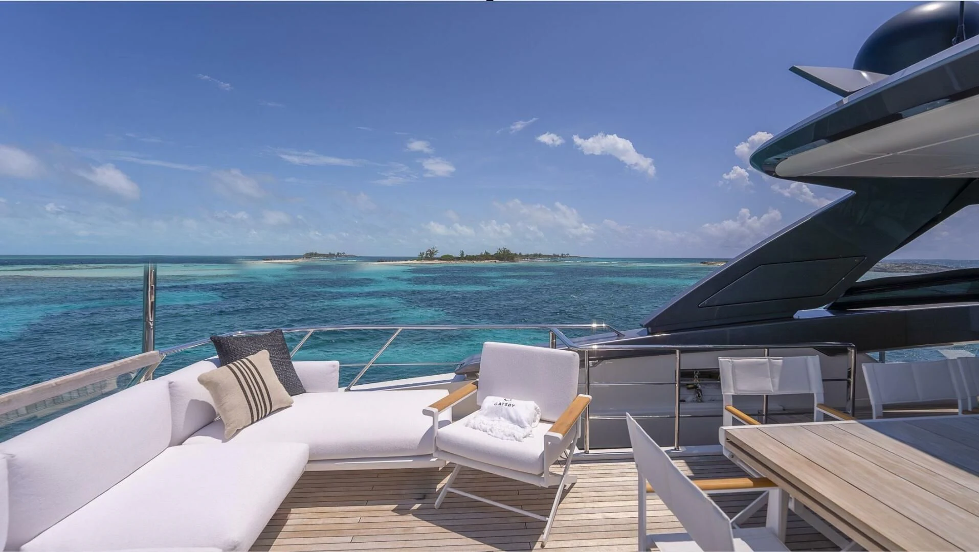 a deck with chairs and a body of water in the background aboard GATSBY Yacht for Charter