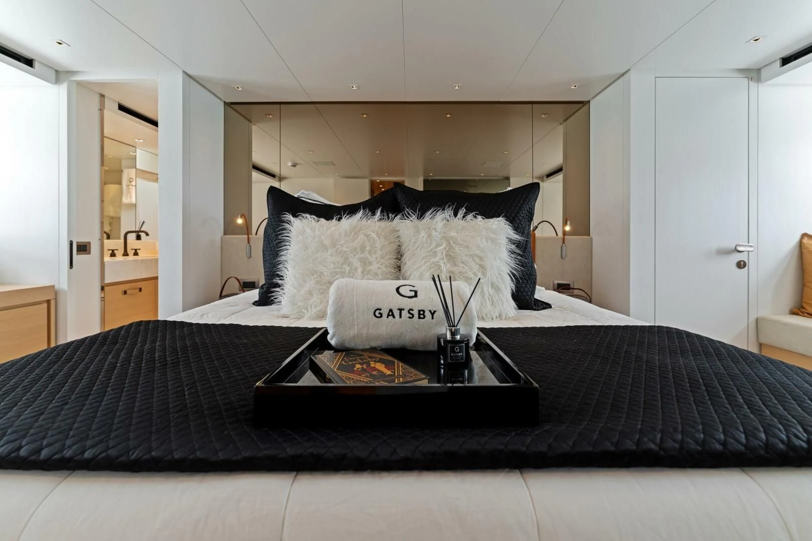 a bed with a black and white bed spread and a black coffee table aboard GATSBY Yacht for Charter