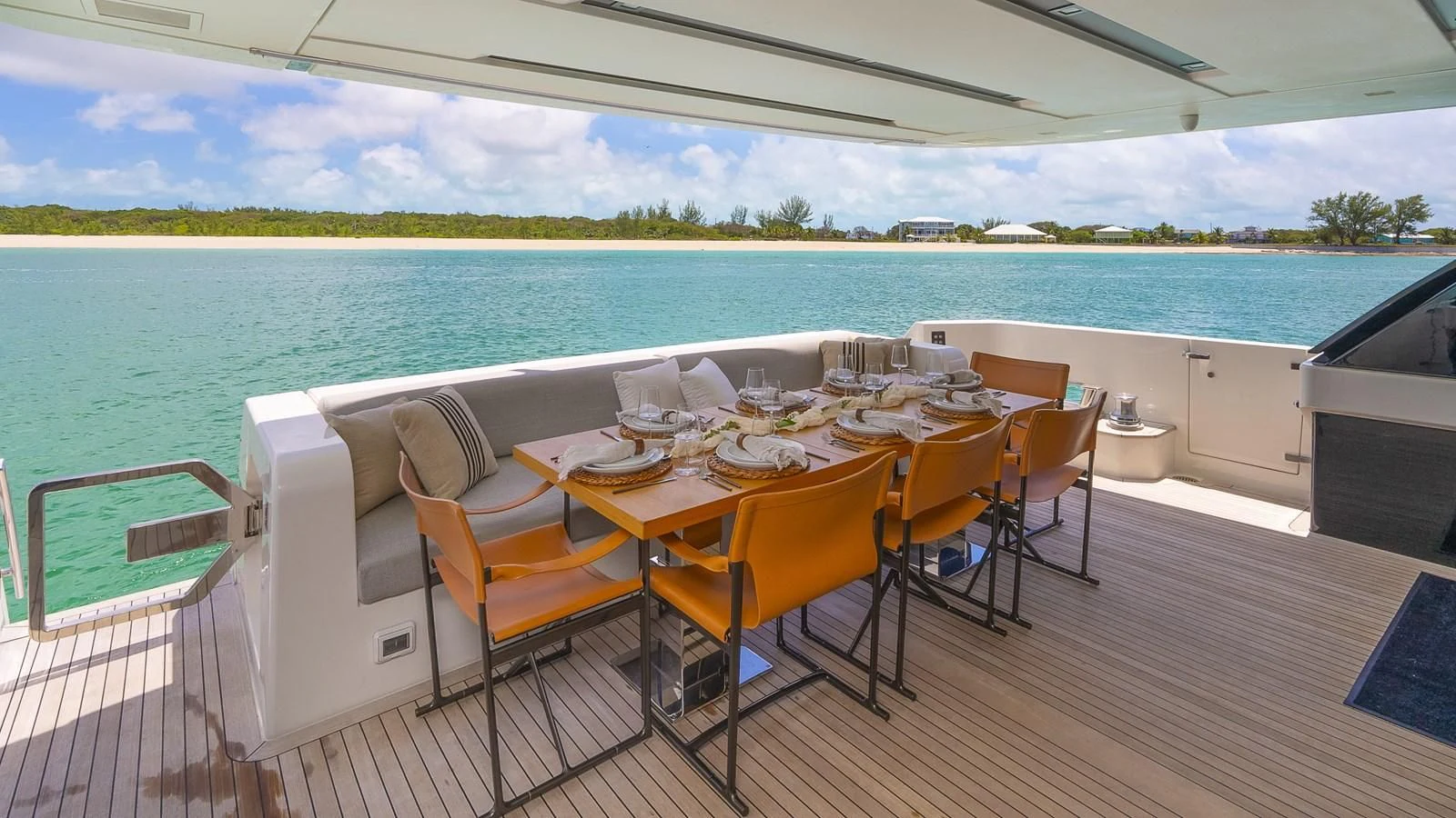 a table set for a meal on a deck overlooking a beach aboard GATSBY Yacht for Charter
