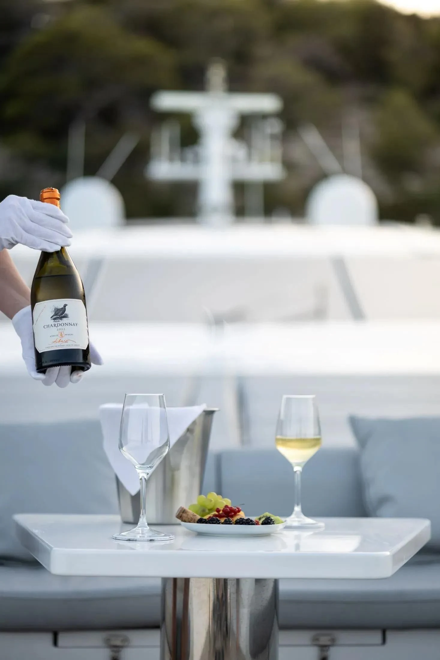 a table with a plate of food and a bottle of wine aboard MAC Yacht for Sale