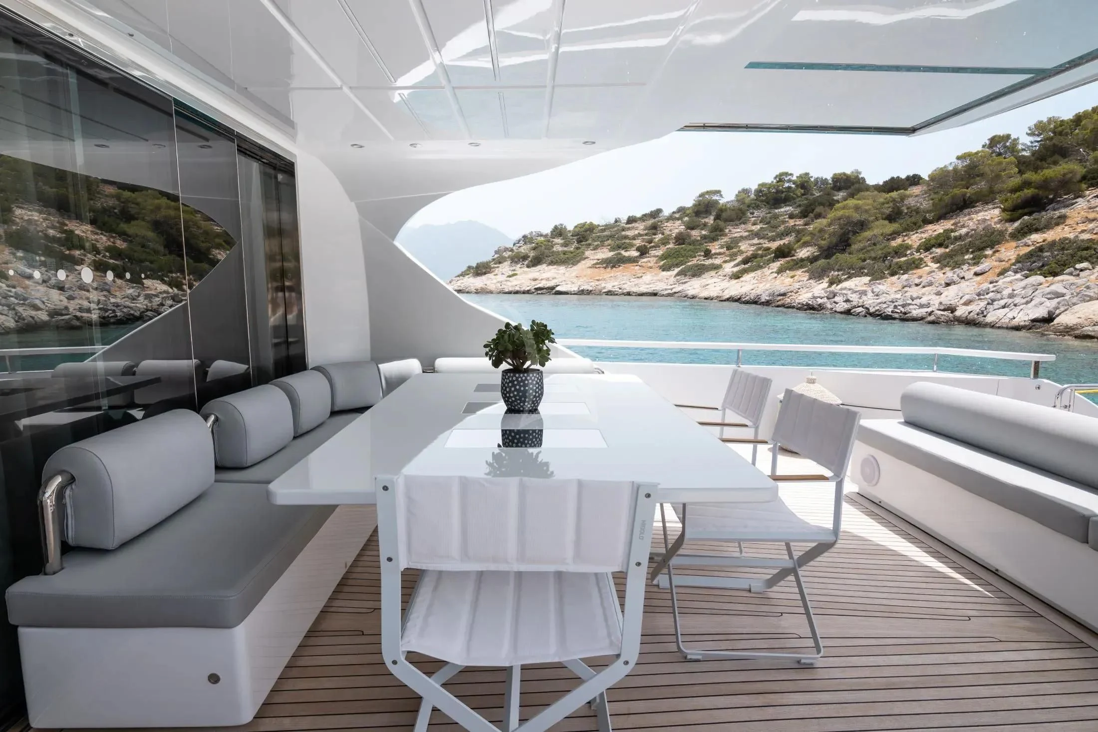 a table and chairs on a balcony overlooking a body of water aboard MAC Yacht for Sale