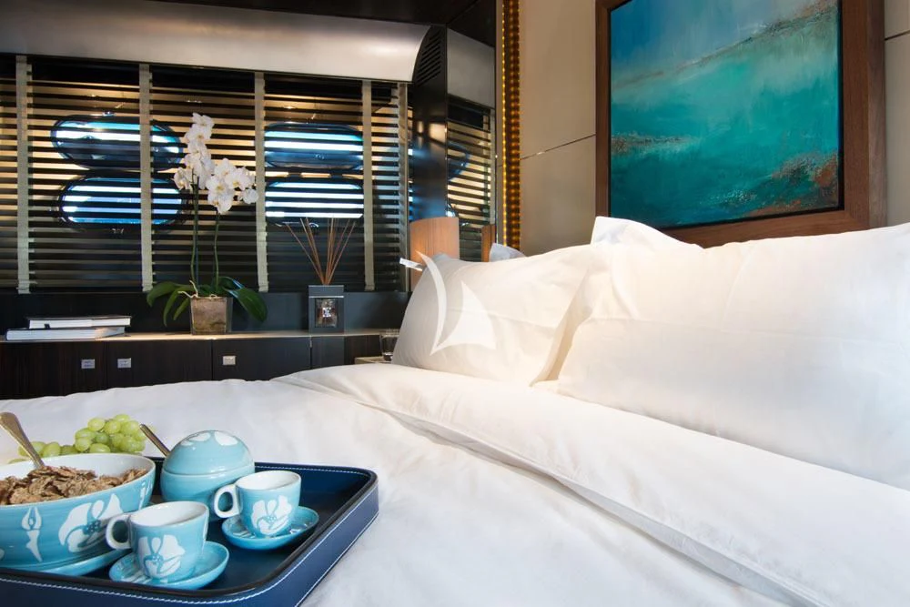 a bed with white sheets and a tray of food on it aboard MAC Yacht for Sale