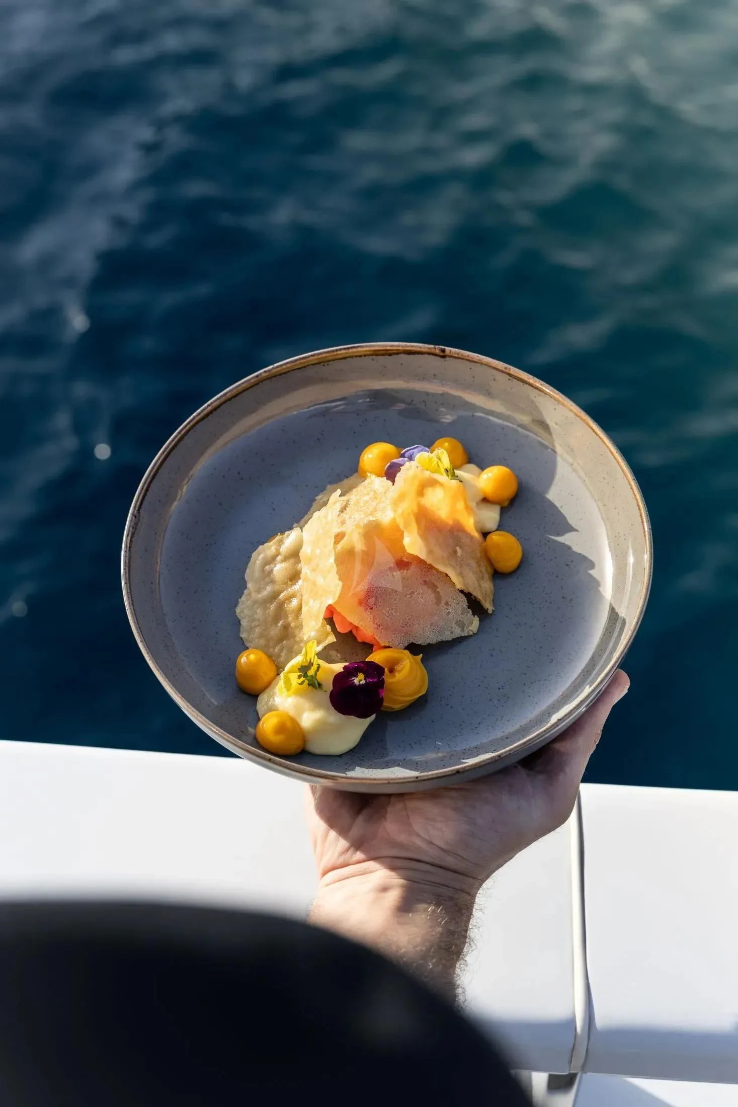 a hand holding a bowl of food aboard MAC Yacht for Sale
