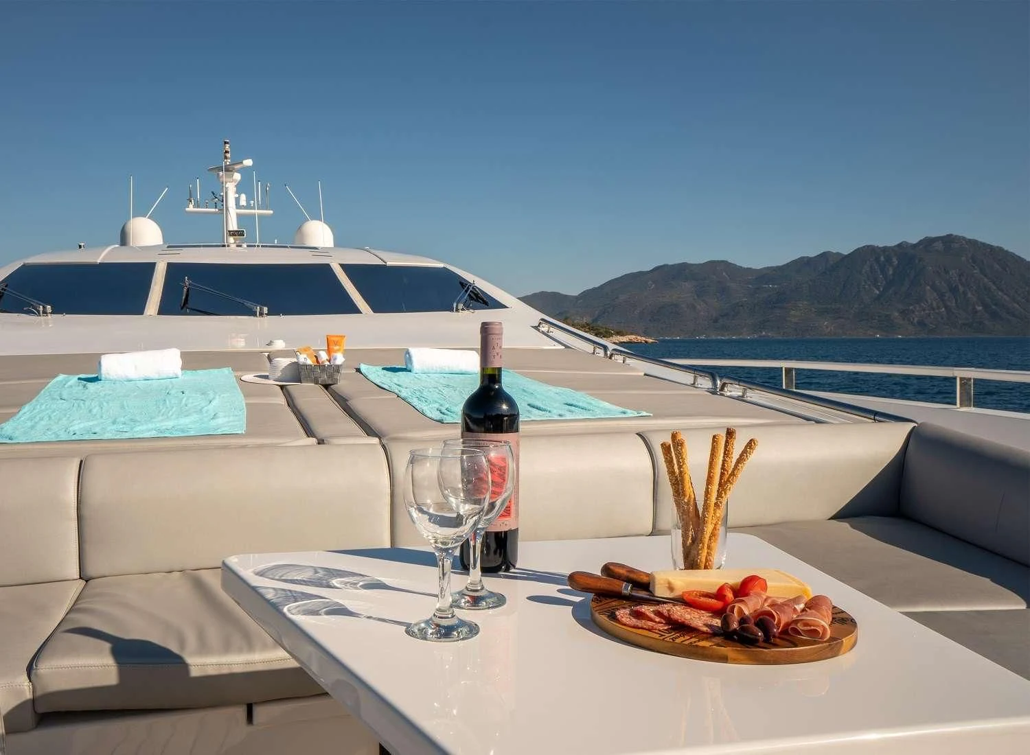 a table with a plate of food and a bottle of wine on it aboard MAC Yacht for Sale