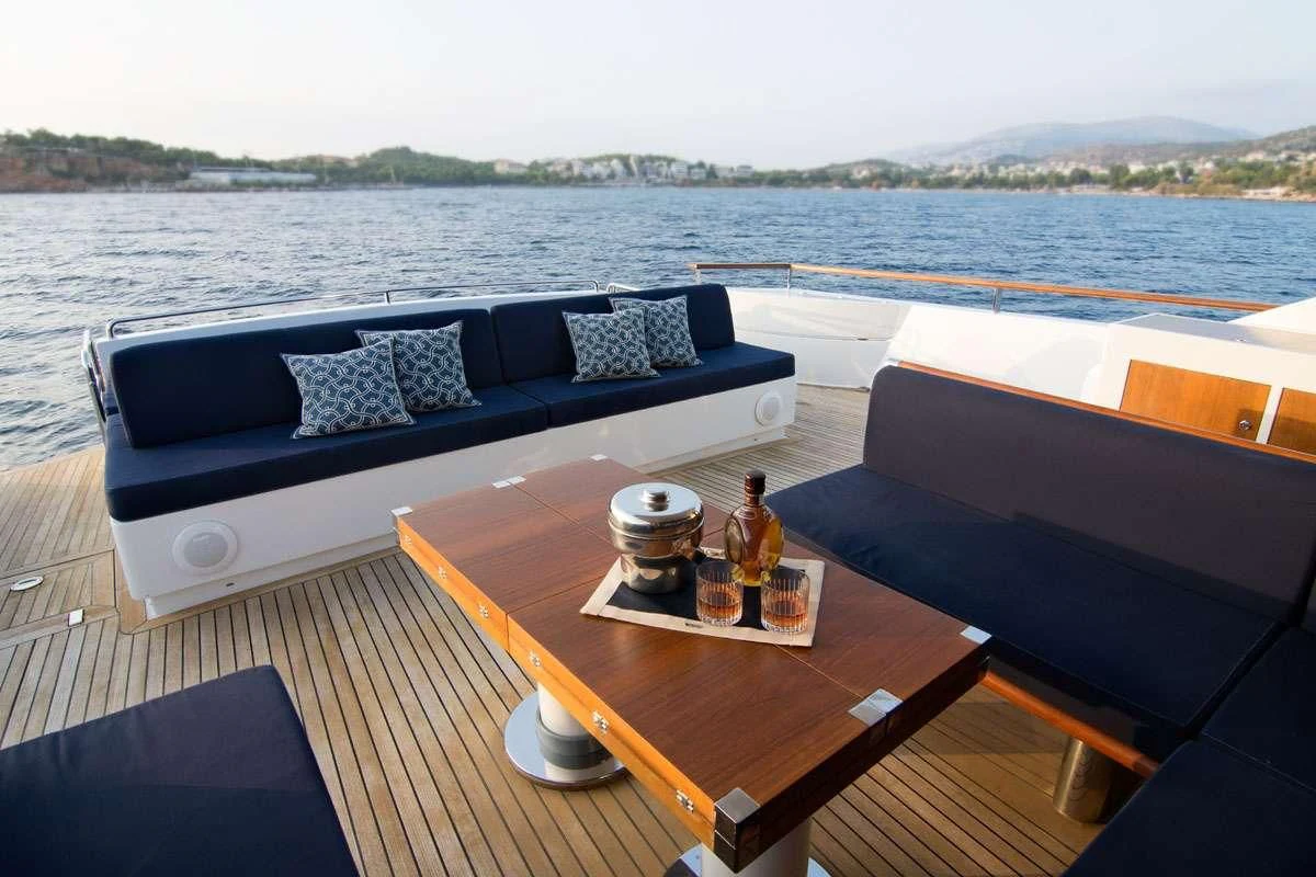 a table with a couch and a table with a bottle of beer on it aboard MAC Yacht for Sale