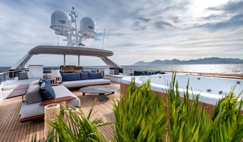 a deck with a pool and a large ferris wheel in the background aboard ALAIA Yacht for Sale