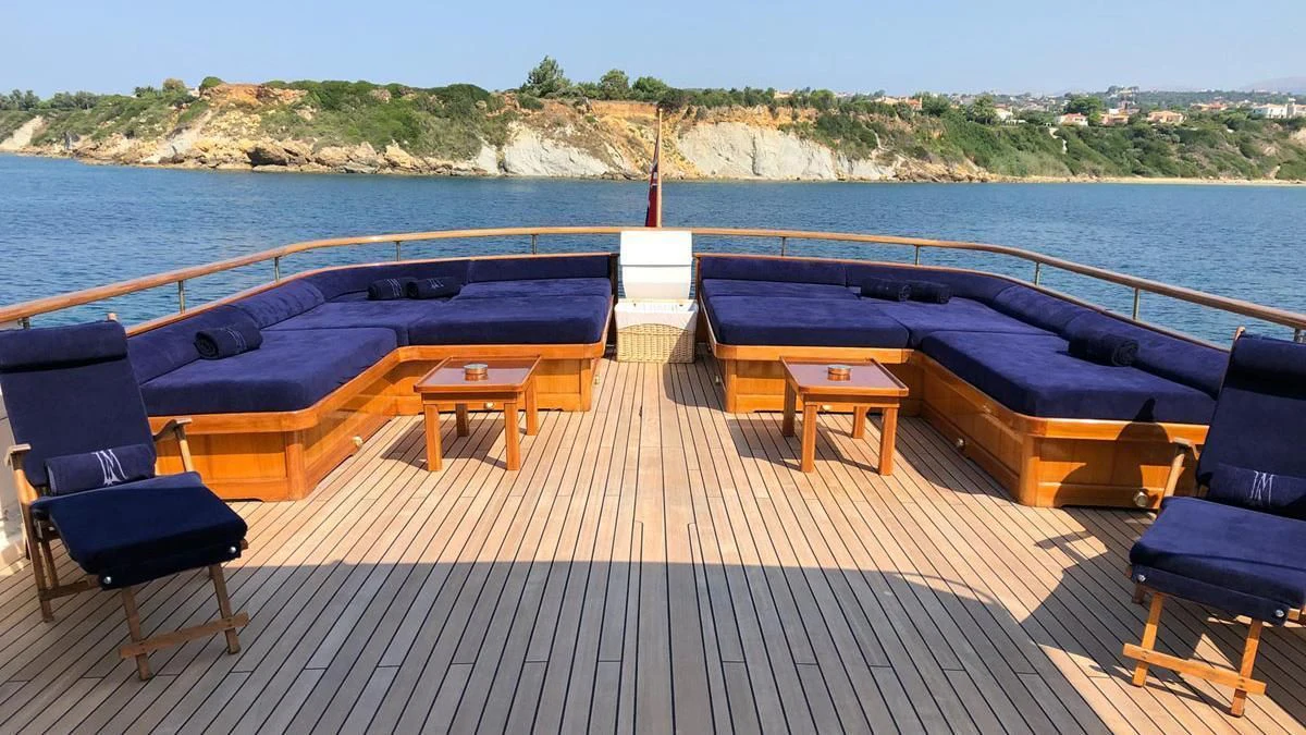 a deck with chairs and tables on it by a body of water aboard LADY MAY OF GLANDORE Yacht for Sale