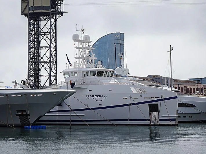 a large white boat in a harbor aboard GARCON Yacht for Sale