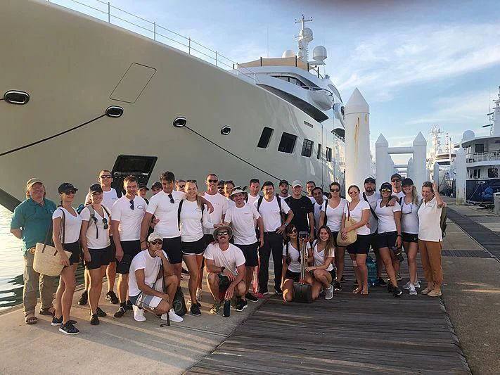 a group of people posing for a photo in front of a helicopter aboard GARCON Yacht for Sale