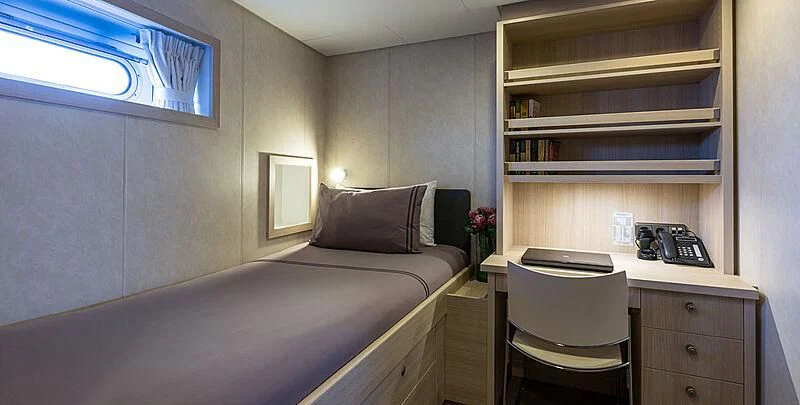 a bedroom with a bed and desk aboard GARCON Yacht for Sale