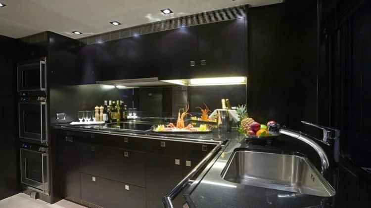 a kitchen with black cabinets aboard G-FORCE Yacht for Sale