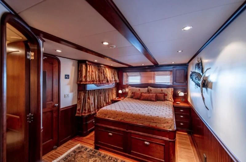 a bedroom with a bed and a dresser aboard HER IDEA Yacht for Sale