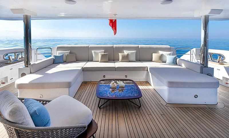 a large white couch with a blue table and a blue rug on a wooden deck next to a aboard MONT-AL LAWZ Yacht for Sale