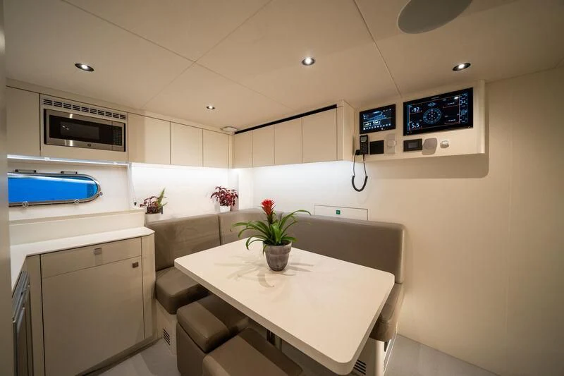 a white kitchen with a table and chairs aboard IKAL Yacht for Sale