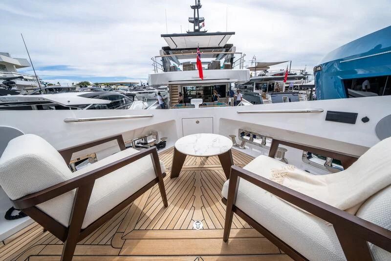 a boat with white fur and a white table and chairs on a deck aboard IKAL Yacht for Sale