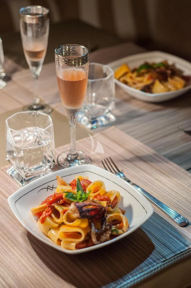 a plate of food and a glass of beer on a table aboard FAR AND WIDE Yacht for Sale