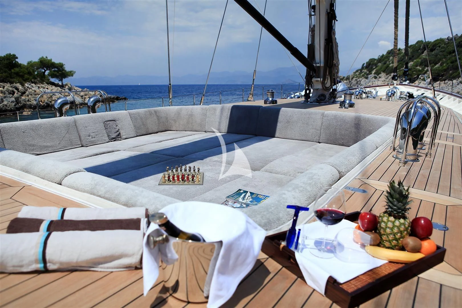 a table with a chair and a pool with a tree and a beach and water in the background aboard ZELDA Yacht for Sale