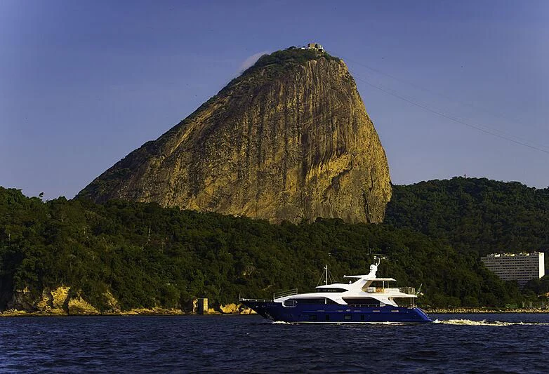 a boat in the water by a large rock mountain aboard BLUE BAY Yacht for Sale
