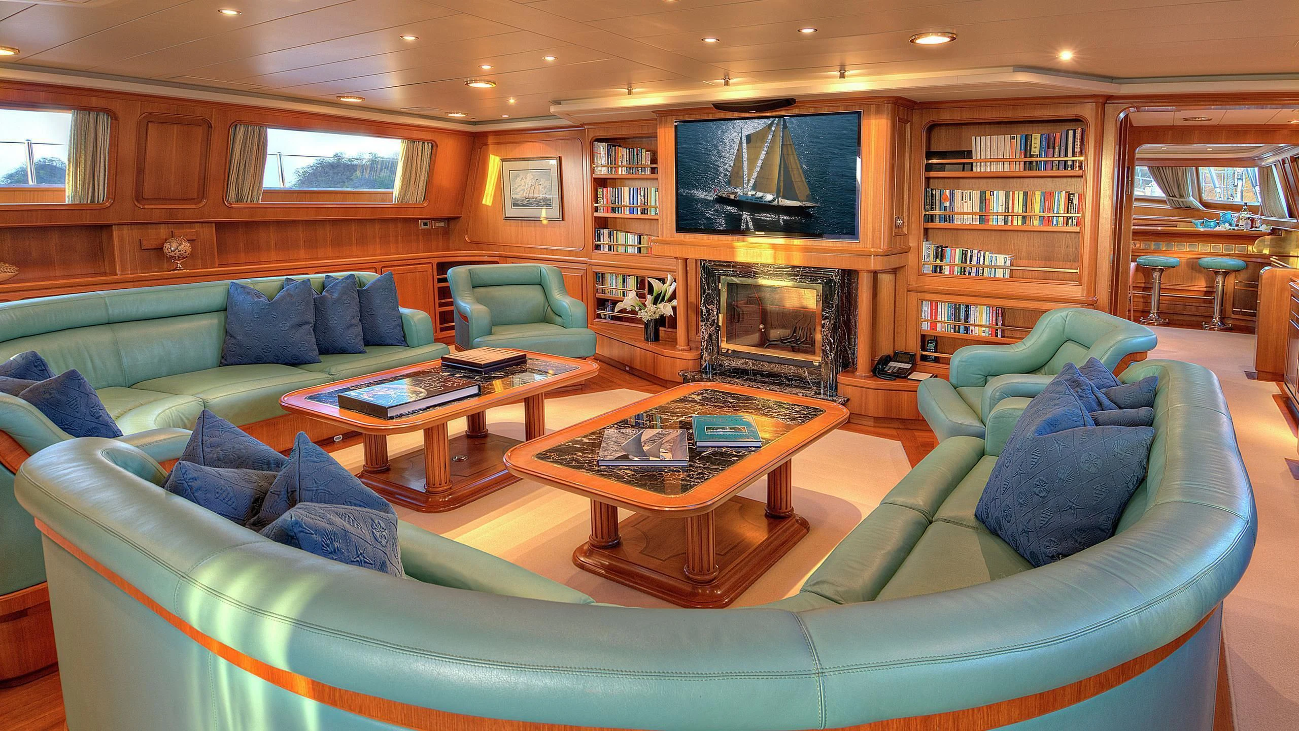 a living room with a blue couch and a fireplace aboard MORNING GLORY Yacht for Sale