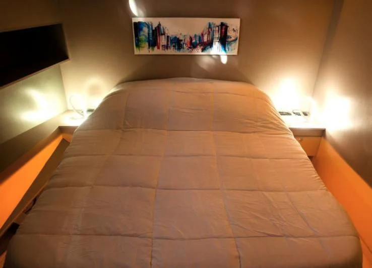 a bed with a red comforter aboard LA MER Yacht for Sale