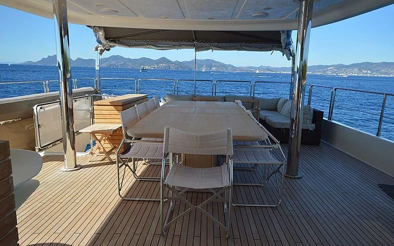 a table and chairs on a deck overlooking a body of water aboard DISPARATE Yacht for Sale