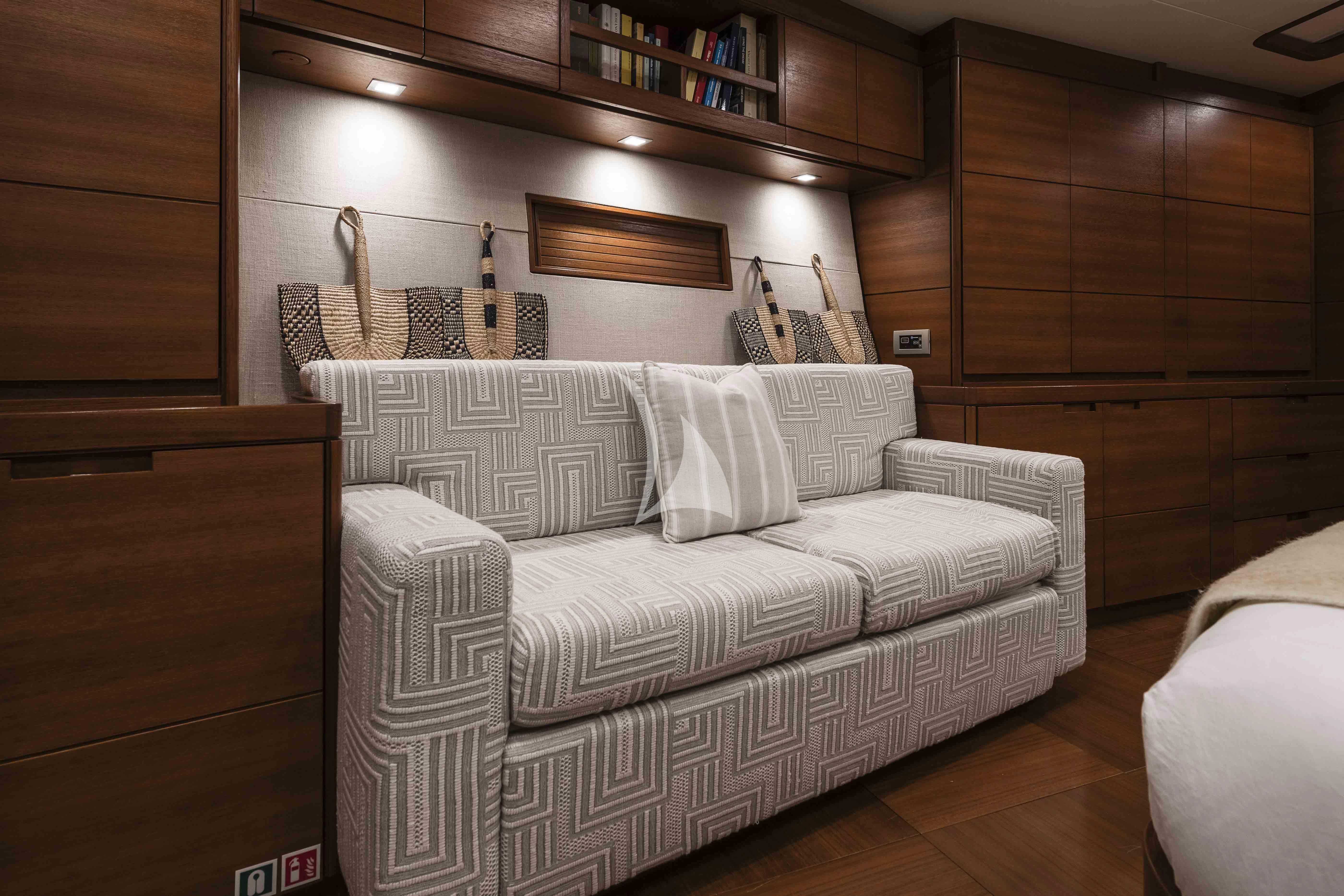 a room with a couch and a shelf with books aboard ACAIA Yacht for Sale