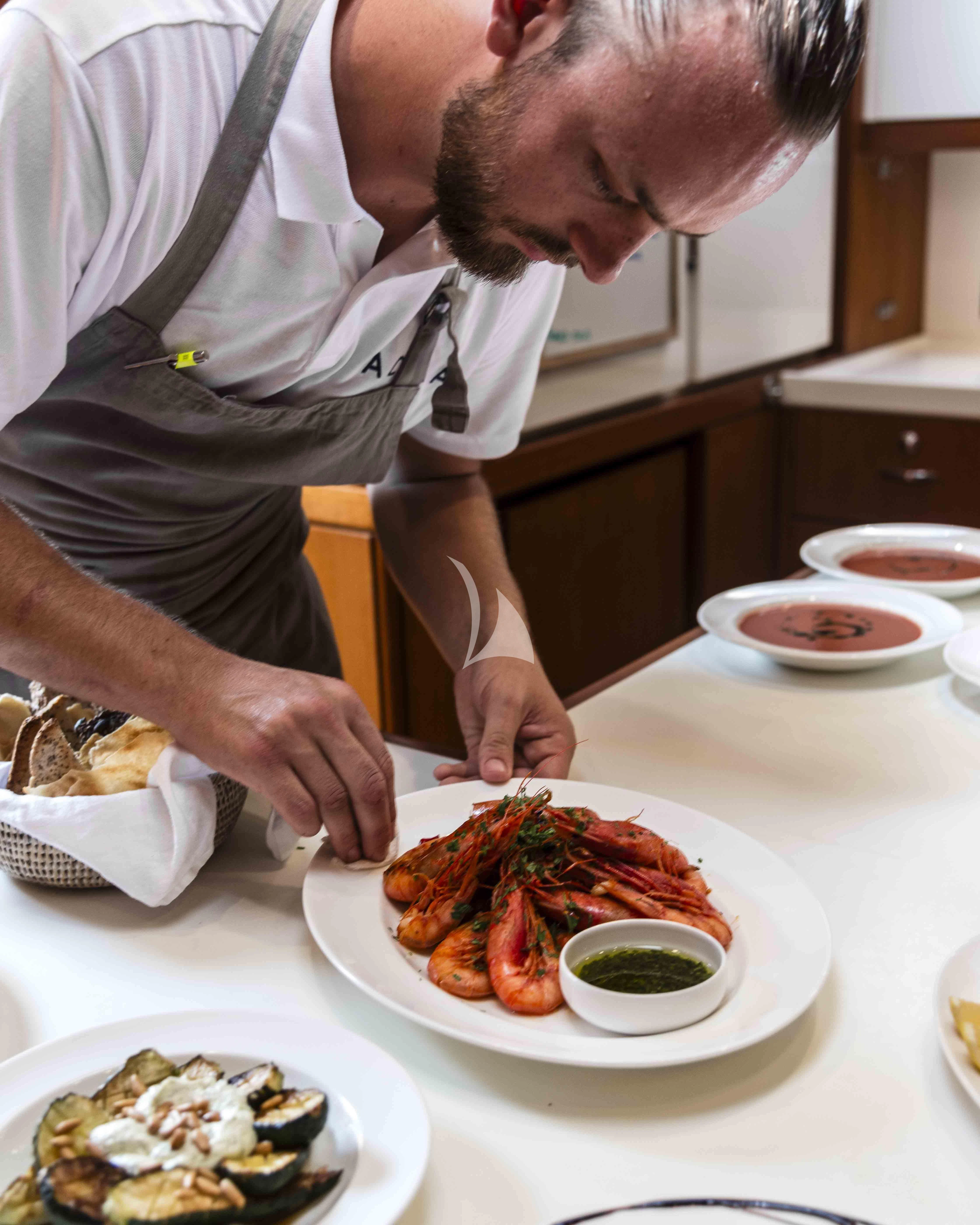 a man preparing food in a kitchen aboard ACAIA Yacht for Sale