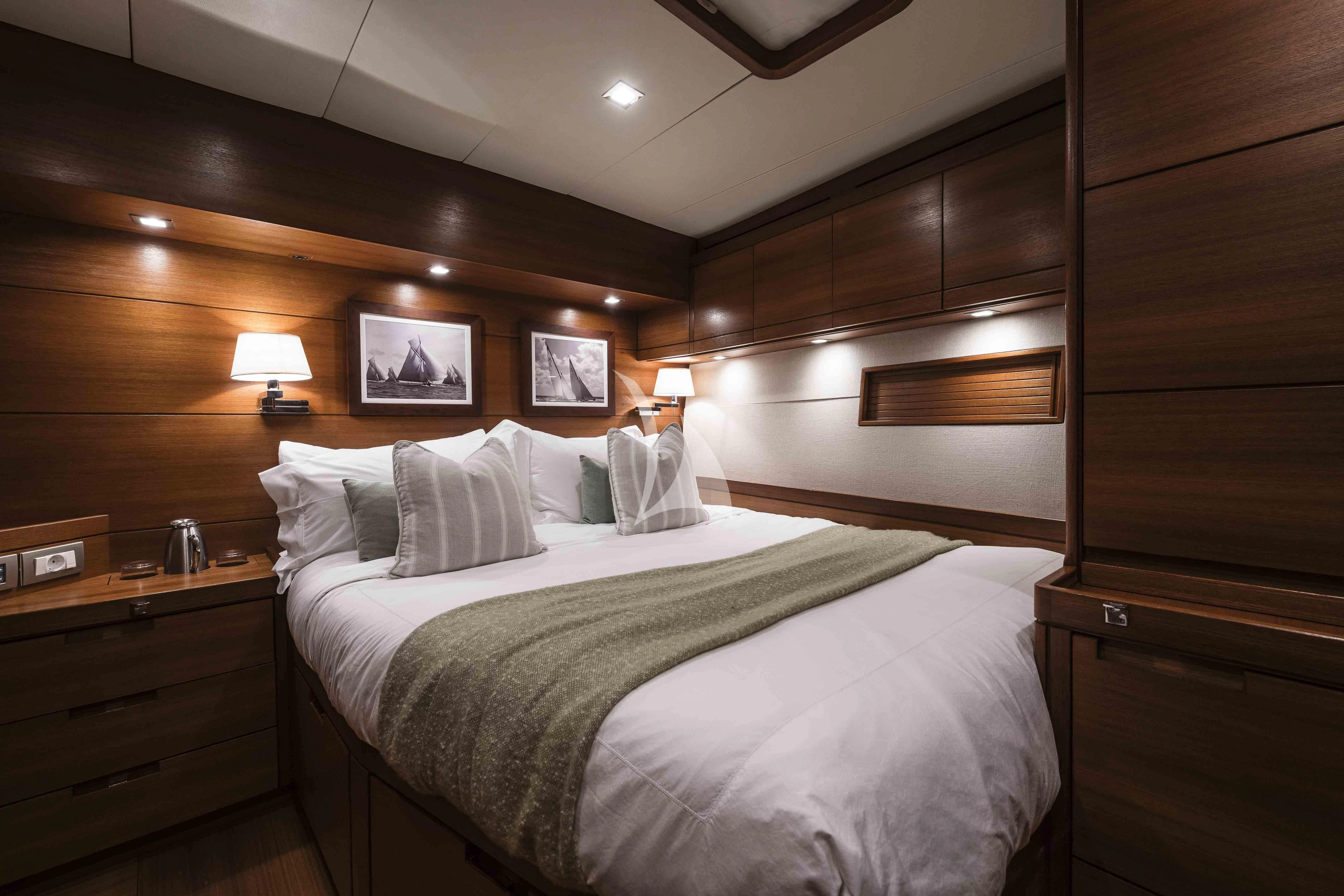 a bed with a white sheet and pillows in a room with wood walls aboard ACAIA Yacht for Sale
