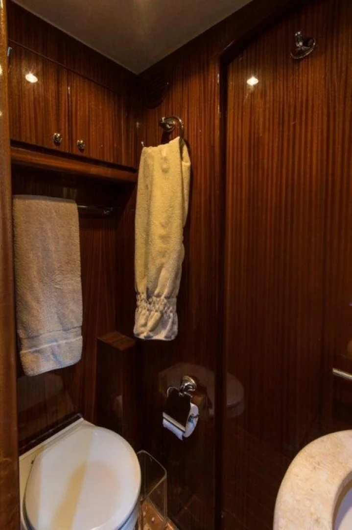 a bathroom with a toilet and a towel on the wall aboard DUNIA Yacht for Sale