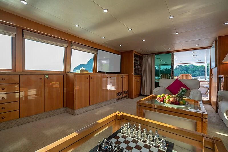 a room with wooden cabinets and a table with a couch and a window aboard AJAO Yacht for Sale