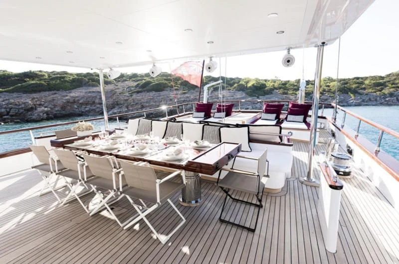 a deck with tables and chairs on it aboard THAT'S AMORE Yacht for Sale