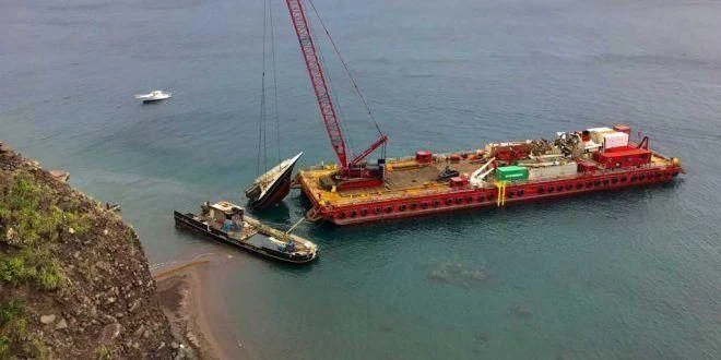a large red crane next to a boat in the water aboard ELSA Yacht for Sale