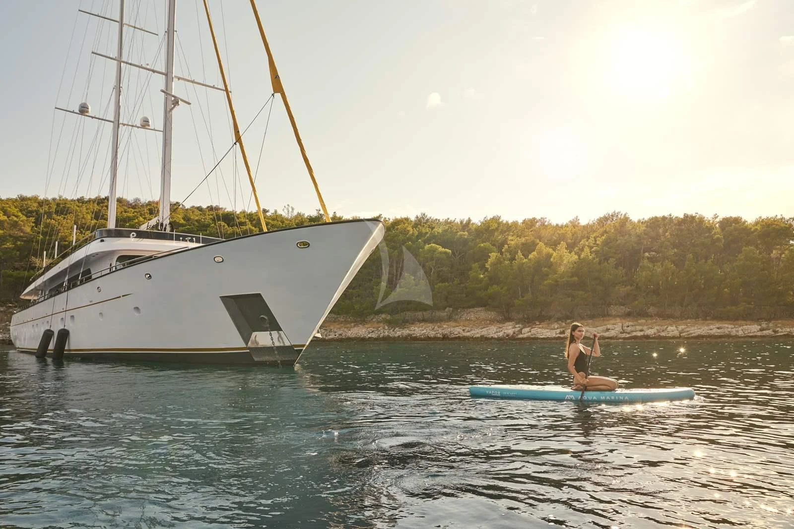 a person on a surfboard in the water next to a boat aboard ANIMA MARIS Yacht for Sale