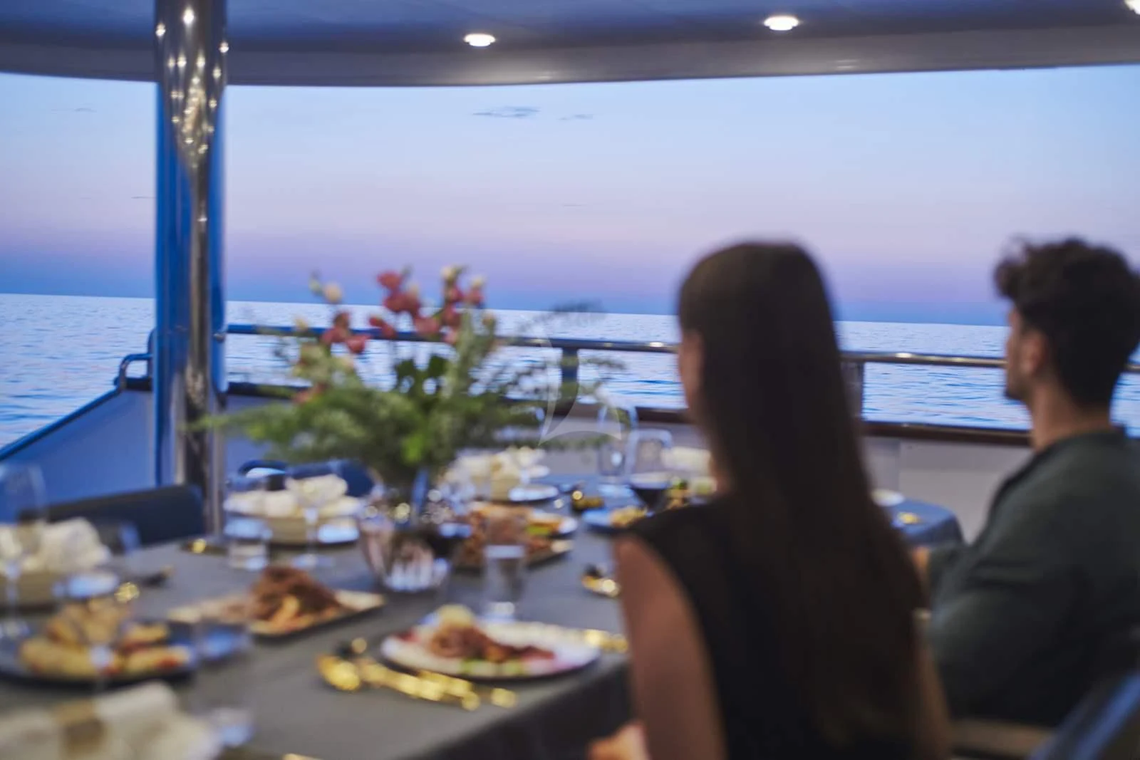 a couple sitting at a table with food on it aboard ANIMA MARIS Yacht for Sale