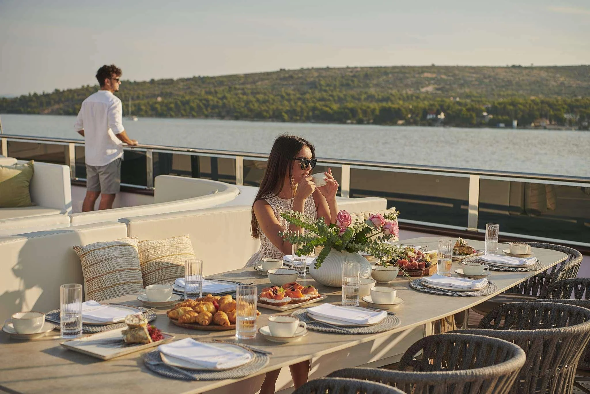 a man and woman eating at a table with a large body of water behind them aboard ANIMA MARIS Yacht for Sale