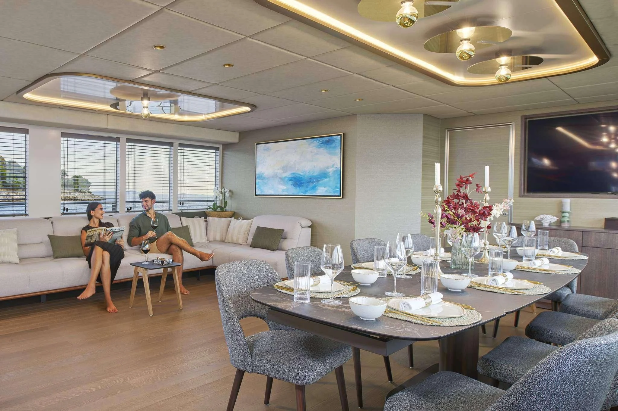 a man and a woman sitting at a table in a room with a large screen and a large aboard ANIMA MARIS Yacht for Sale