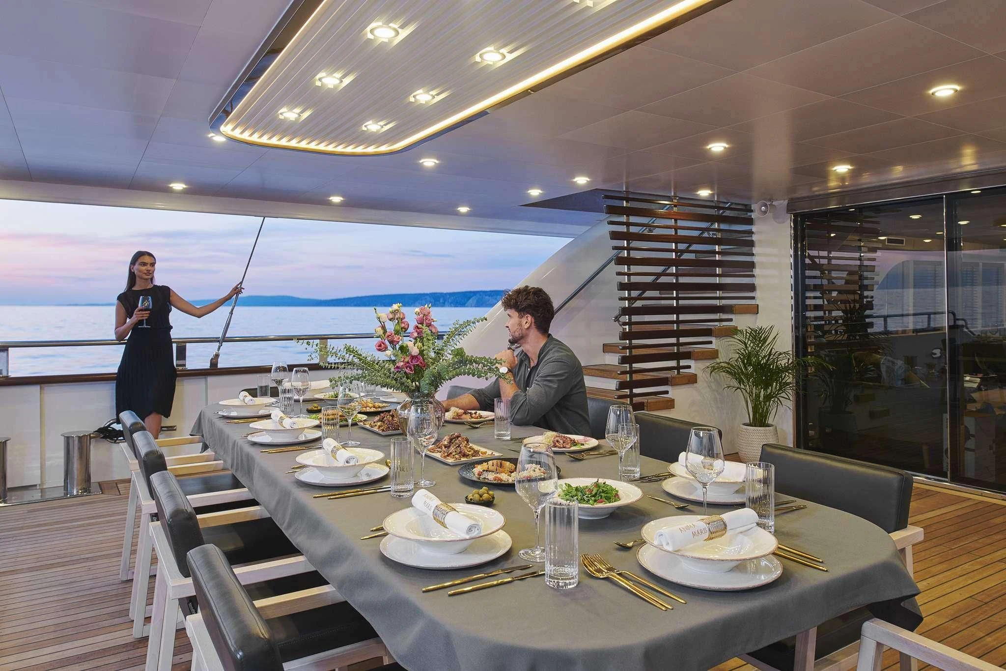 a man and woman sitting at a table with food on it aboard ANIMA MARIS Yacht for Sale