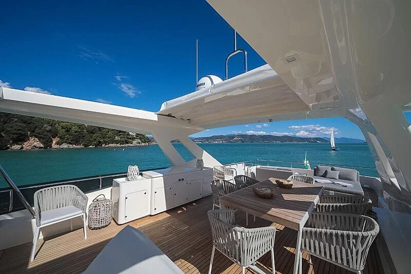 a patio with a table and chairs on it by a body of water aboard RURI Yacht for Sale