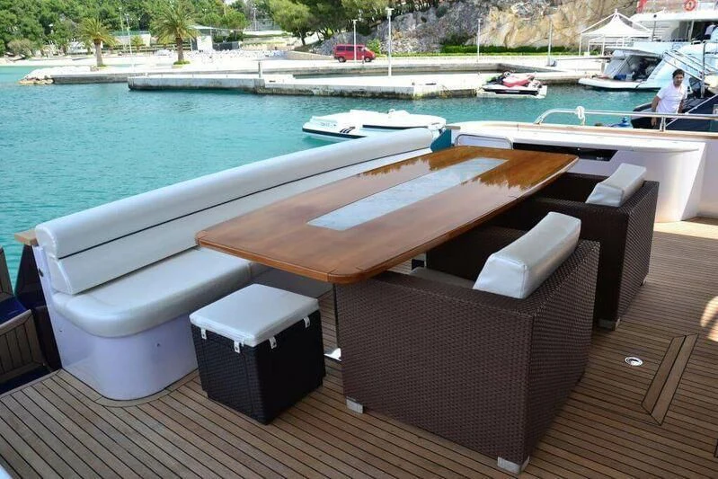 a deck with a table and chairs on it by a body of water aboard HITECH RACING Yacht for Sale