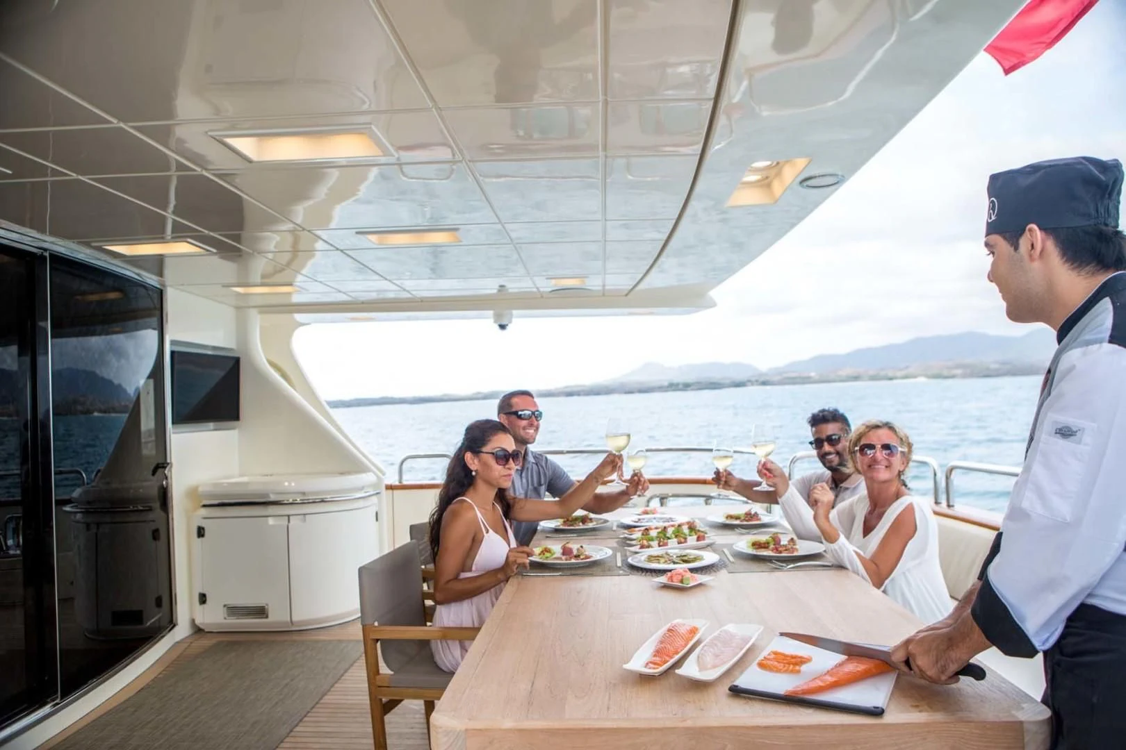 a group of people sitting around a table with food on it aboard AMANECER Yacht for Sale