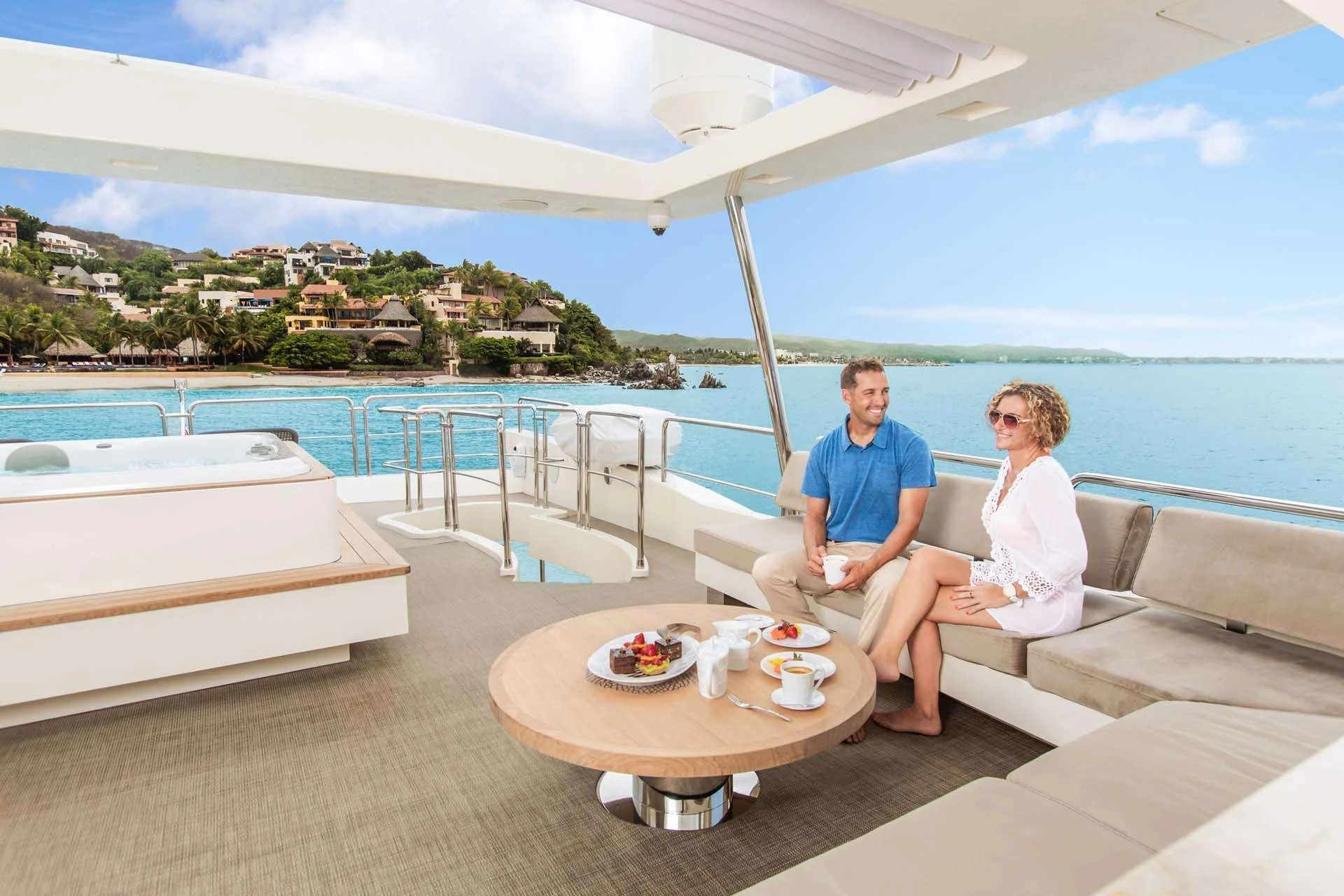 a couple sitting on a couch on a balcony overlooking a body of water aboard AMANECER Yacht for Sale