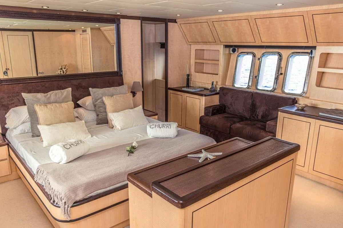 a bedroom with a bed and a leather couch aboard CHURRI Yacht for Sale