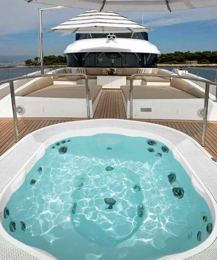 a swimming pool with a large white boat in the background aboard ASIA POSEIDON Yacht for Sale