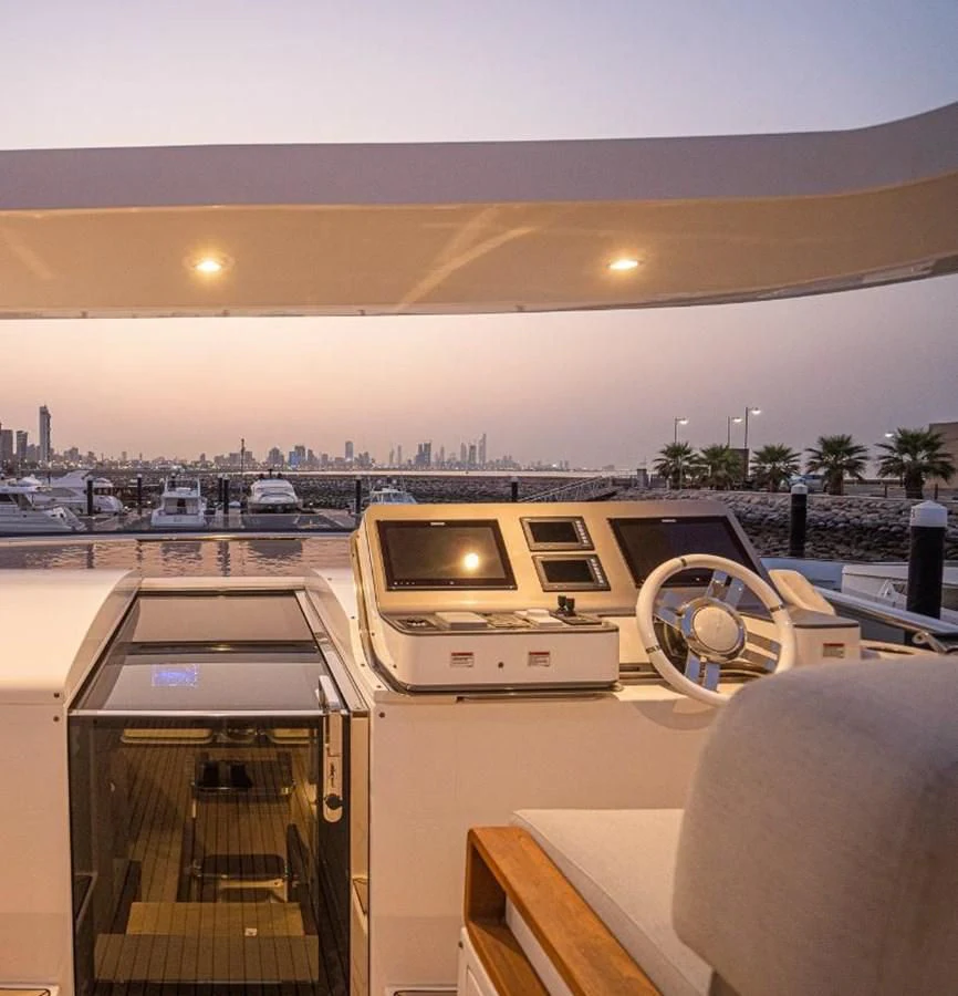 a large white vehicle in a large room with a large body of water and boats in the background aboard LULWA Yacht for Sale