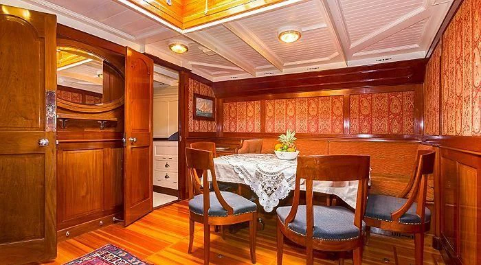 a dining table and chairs in a room with wood walls aboard MARIQUITA Yacht for Sale